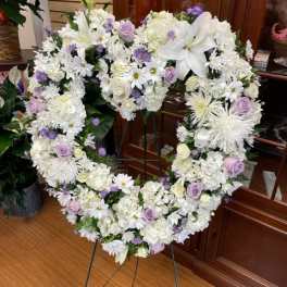 Heart-shaped white floral wreath on a stand with lavender accents