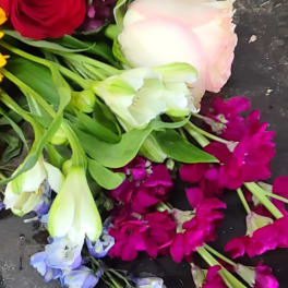 Mixed bouquet with roses, tulips, and purple blooms on a dark surface