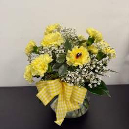 Yellow carnations in a round vase with a gingham bow