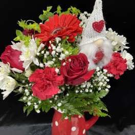 Red and white flower arrangement in a polka-dot mug with a gnome decoration