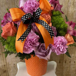 Pink and lavender bouquet in an orange vase with a polka-dot ribbon