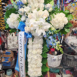 White floral standing cross with lilies and roses on an easel