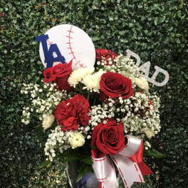 Red roses and white flowers in a vase with baseball-themed decorations