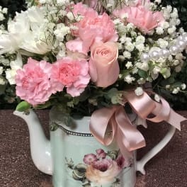 Pink and white flowers arranged in a decorative watering can