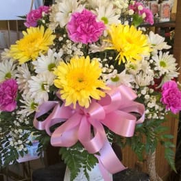 Bouquet of yellow and white daisies with pink carnations in a white vase