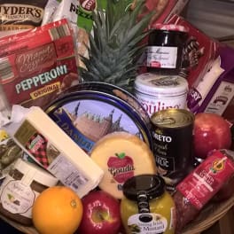 Gift basket with assorted snacks, cheese, fruit, and a pineapple centerpiece