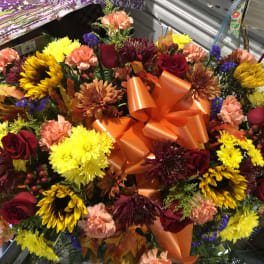 Large mixed bouquet with roses, chrysanthemums, and carnations in orange wrap
