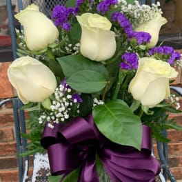 Bouquet of cream roses with purple filler in a glass vase