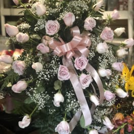 Pink roses and rosebuds arranged with baby's breath and a pink ribbon bow