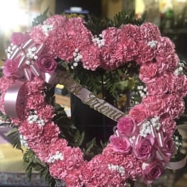 Pink floral heart wreath with roses and ribbon on a stand