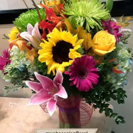 Colorful mixed bouquet in a glass vase with sunflowers, lilies, and chrysanthemums