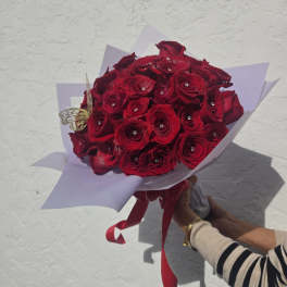 Bouquet of red roses wrapped in pale lavender paper with a red ribbon