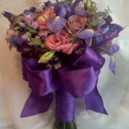 Purple and pink bouquet with roses and irises wrapped in satin ribbon