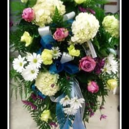Standing floral spray with white blooms, pink roses, and blue ribbon