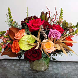 Mixed bouquet of roses and tropical accents in a glass vase
