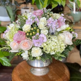 Pink and white roses arranged in a silver pedestal vase