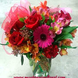 Bouquet of red roses and pink gerbera daisies in a glass vase
