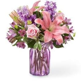 Pink lily and rose bouquet in a purple glass vase