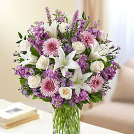 Bouquet of white lilies, pink flowers, and cream roses in a glass vase