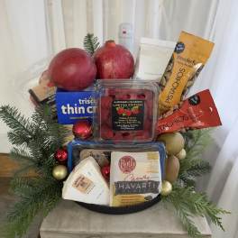 Holiday gift basket with fruit, cheese, crackers, nuts, and greenery
