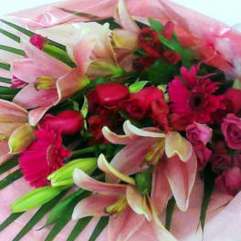 Bouquet of pink lilies and red flowers wrapped in pink paper