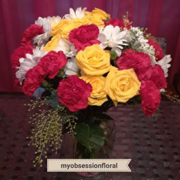 Bouquet of yellow roses, red carnations, and white daisies in a vase