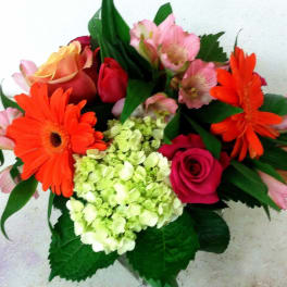 Bouquet of orange gerbera daisies, pink roses, and pale green hydrangea