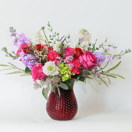 Mixed pink and purple bouquet in a red glass vase