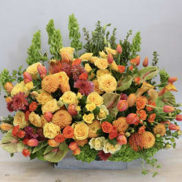 Large orange and yellow floral arrangement in a rectangular container
