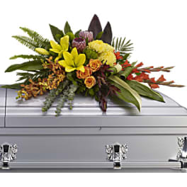 Floral casket spray with yellow lilies and orange roses on a silver casket