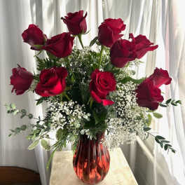 Red roses in a red glass vase with white filler flowers