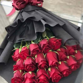 Bouquet of red roses wrapped in black paper with a burgundy bow