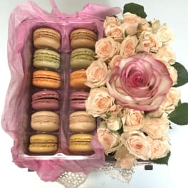 Macaron gift box beside a bouquet of pale pink roses