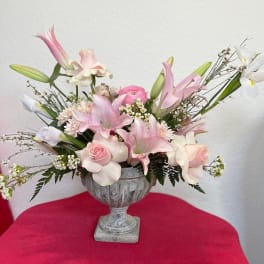 Pink and white floral arrangement in a gray urn vase