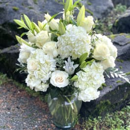 White roses and hydrangeas arranged in a glass vase