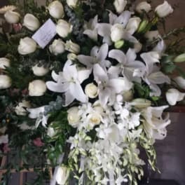 Large white funeral spray on an easel with lilies and roses