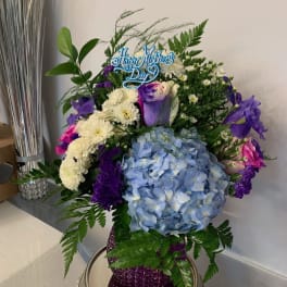 Blue hydrangea bouquet with purple and white flowers in a purple vase