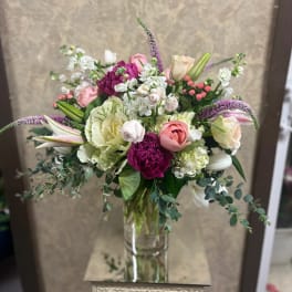Mixed bouquet of pink, white, and purple flowers in a glass vase