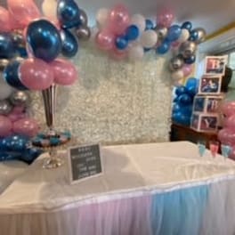 Pink, blue, and silver balloon decorations around a draped table