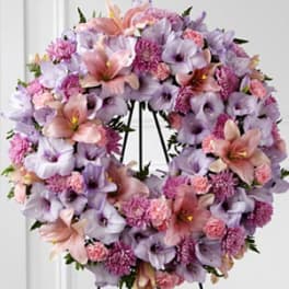 Lavender and pink floral wreath with lilies and carnations on a black easel