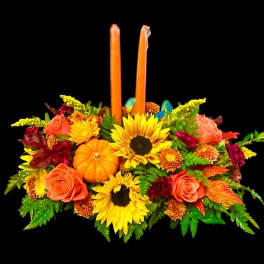 Autumn floral centerpiece with two orange candles and a small pumpkin