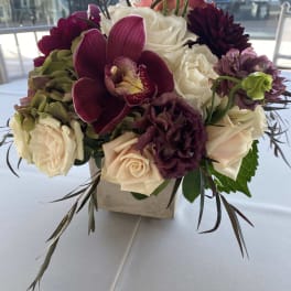 Bouquet of white and burgundy flowers in a square vase