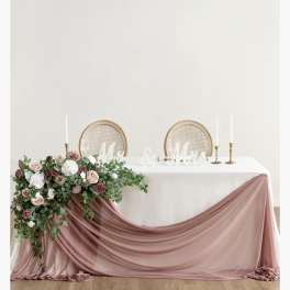 Wedding table with pink floral arrangement and draped blush fabric