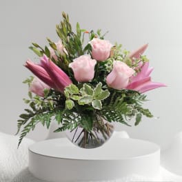Pink roses and lilies arranged in a clear glass vase