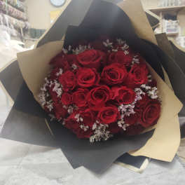 Bouquet of red roses with small white filler flowers in black and tan wrap