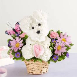 White teddy bear floral arrangement in a wicker basket with pink and purple flowers