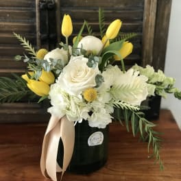 White roses and hydrangeas with yellow tulips in a black vase