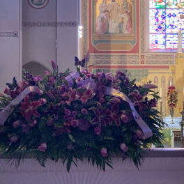 Large purple floral arrangement with ribbon in a church