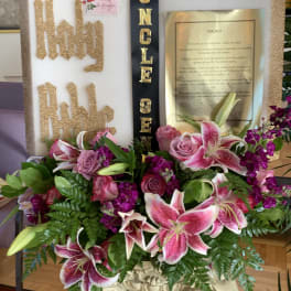 Pink lilies and roses arranged around a memorial display with gold lettering