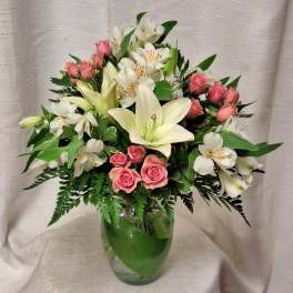 Pink roses and white lilies arranged in a clear glass vase